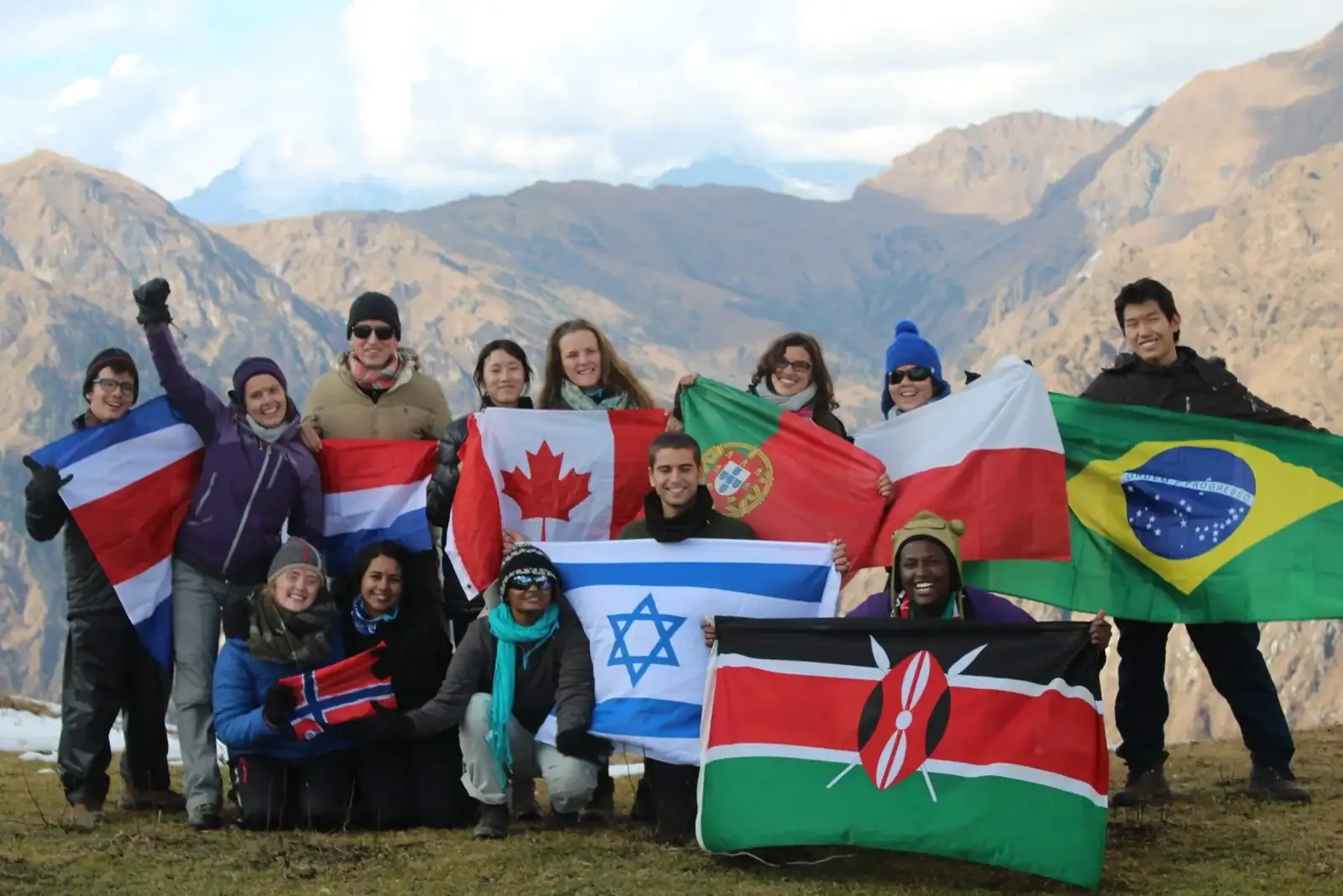 Students holding the flags of many nations on a hillside